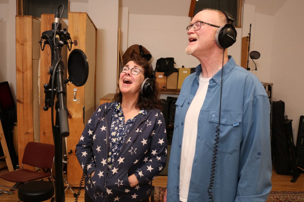 Robin and Eric Lindahl singing in front of microphone.